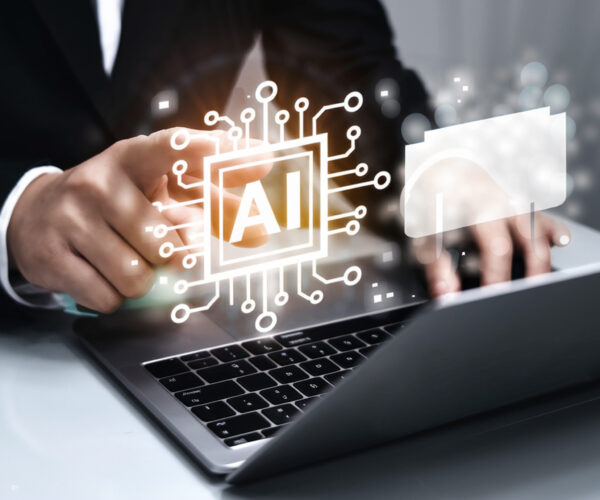 Hands typing on a laptop with glowing AI circuit graphics projected over the keyboard to symbolize artificial intelligence innovation